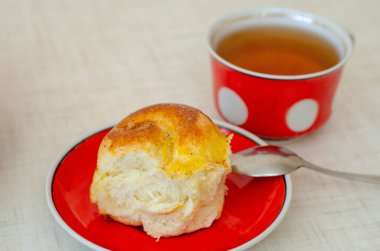 Bir dilim limonlu turta ve kırmızı tabakta bir fincan çay.