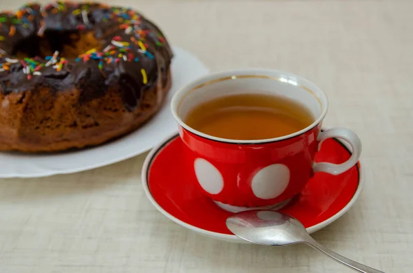 Round cupcake with chocolate torring on the white plate and red cup