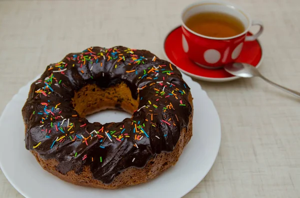 Round cupcake with chocolate torring on the white plate and red cup