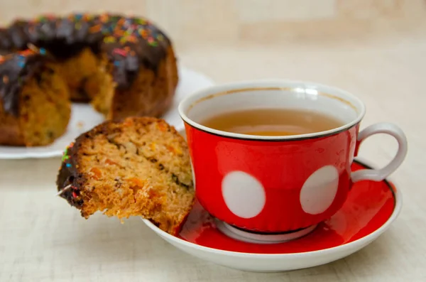 Round cupcake with chocolate torring on the white plate and red cup