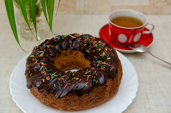 Round cupcake with chocolate torring on the white plate and red cup