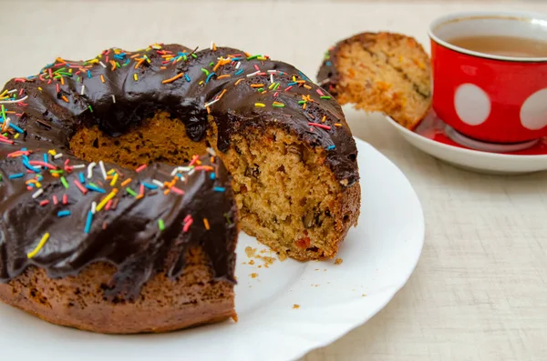 Round cupcake with chocolate torring on the white plate and red cup
