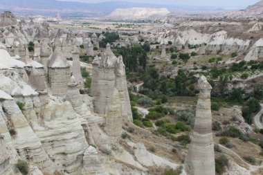 Ufukta dağlar ve tepeler olan mavi bir gökyüzünün altında rüzgarın oluşturduğu garip şekilli uzun beyaz taşlardan oluşan bir vadi.