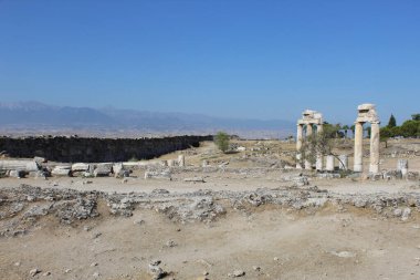 Porticos, parlak mavi gökyüzünün altında yeşil bir bitki örtüsüne karşı dağlar ve ufukta bir uçurum