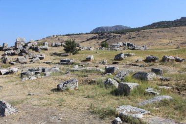Düzenli şekilli gri taşlar, belki de kadim mezarların kalıntıları, parlak güney gökyüzünün altındaki vadideki kuru ot ve kumların arasında.