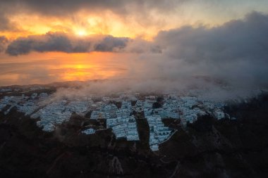 Santorini, Imerovigli köyü, gün doğumunda kaldera manzaralı, beyaz mimarili manzaralı hava manzaralı, Ege Denizi, bulutlu ve güneşli renkli gökyüzü, dış seyahat arka planı, Yunanistan