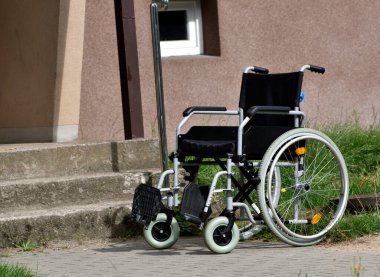 Merdivenlerin önündeki kaldırımda duran tekerlekli sandalye mimari bir bariyerdir.