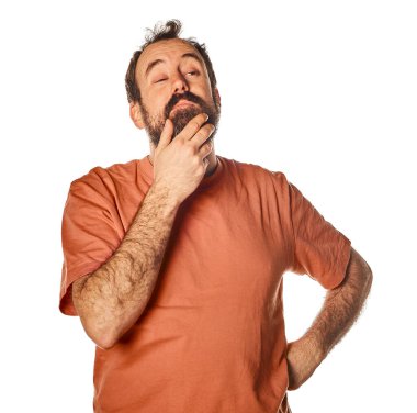 studio portrait of bearded man in casual clothes thoughtful and doubtful. Touching his chin with his hand and with amused expression.
