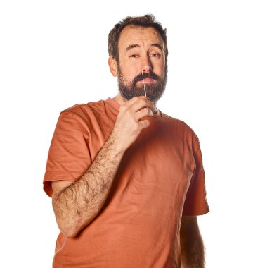 40 'lı yaşlarda sakallı bir adam ağlayan gözlerle ve rahatsız edici bir ifadeyle hızlı bir antijen testi yapıyor. Beyaz izole arkaplan