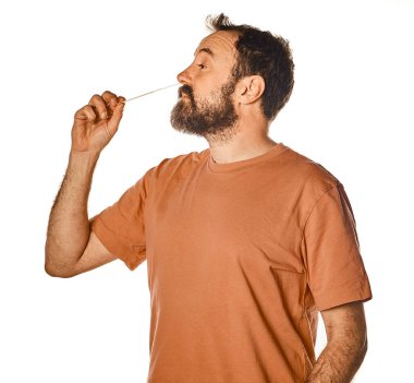 Yaşlı sakallı adam günlük kıyafetlerle hızlı bir burun antijeni testi yapıyor, 40 'lı yaşlarda beyaz..