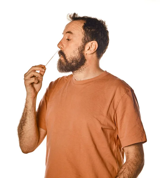 Sakallı adam nahoş bir ifadeyle antijen testi yapıyor. Reklam için beyaz izole edilmiş arka planda. Sınava girerken rahatsız..