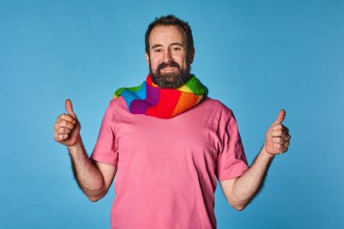 Sakallı biseksüel lgtb erkeği, biseksüel, lgtb gurur renginde bir eşarp takıyor. Karizmatik bir şekilde gülümse. Tamam sembol