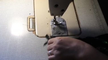 Kanalizasyonun elleri dikiş makinesinin üzerinde dikiş giysileri