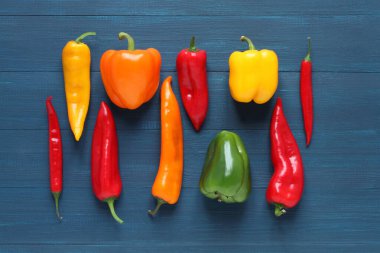 Mavi ahşap bir masada çok renkli tatlı biber, cappi biberi ve acı kırmızı biber. Yukarıdan bak. Yakın çekim..