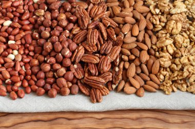 Çiğ fıstık, fındık, ceviz, badem ve keten kumaş üzerinde ceviz. - Yakın çekim. Makro.