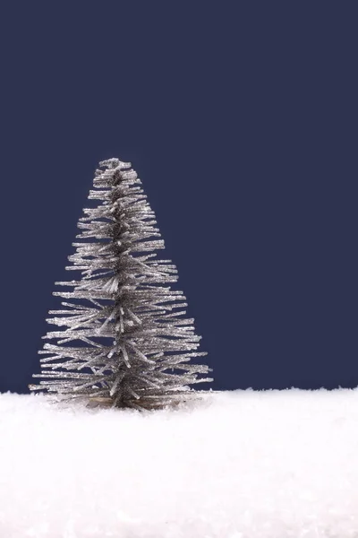ネイビーブルーの背景に人工白い雪のおもちゃの銀クリスマスツリー — ストック写真
