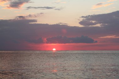 Bir yaz akşamında denizin üzerinde renkli bir gün batımı