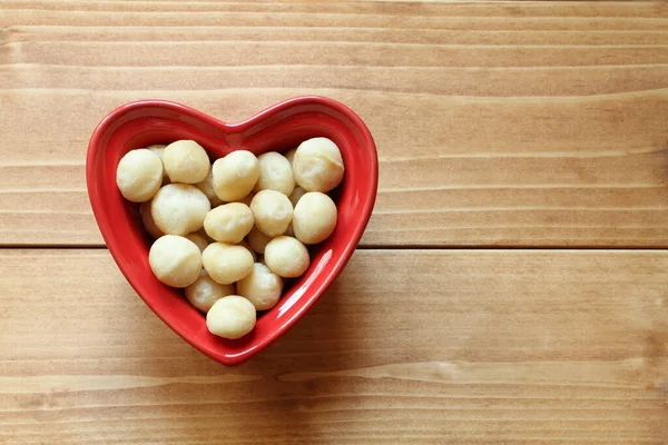 Macadamia Nuts Lie Heart Shaped Ceramic Bowl Which Stands Wooden — Photo