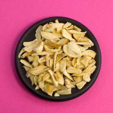 Siyah tabakta kurumuş sarımsak taneleri. Pembe desenli arka plan görünümünde düz bir fotoğraf çek.