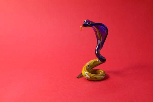 Miniaturní sklo modrý had postava izolovaná na červeném pozadí — Stock fotografie
