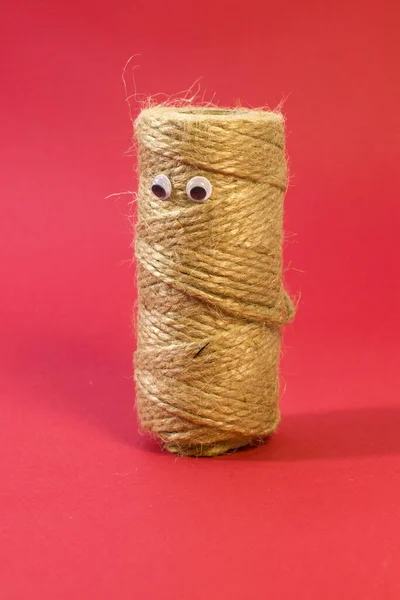 Skein of jute twine with funny eyes. Natural jute twine, macro shot. Jute thread texture on bright red background — Foto de Stock