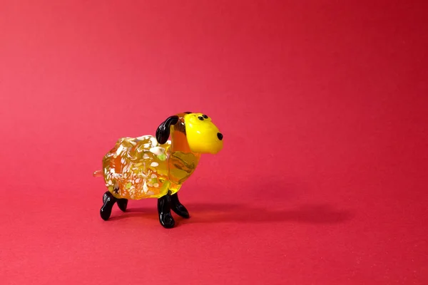 Miniature glass yellow lamb or sheep figurine isolated on red background — Stockfoto