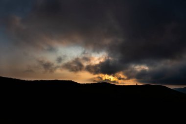 Dağın tepesinde, sırt çantası günbatımı dağlar arka plan üzerinde olan adam silüeti