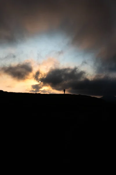 Silueta člověka s batohem na vrcholu hory na pozadí slunce hor — Stock fotografie