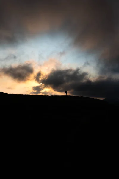 Silueta člověka s batohem na vrcholu hory na pozadí slunce hor — Stock fotografie