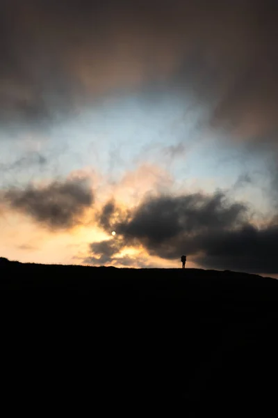 Silueta člověka s batohem na vrcholu hory na pozadí slunce hor — Stock fotografie
