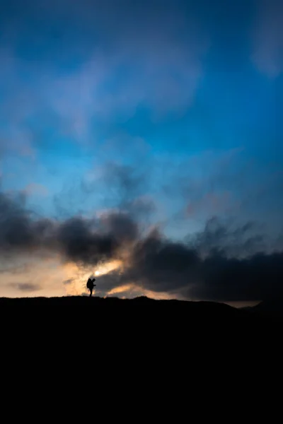 Silhouette of man with backpack at mountain top on background of sunset mountains — Stock Photo, Image