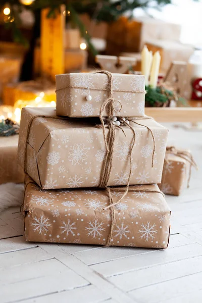 Az ember kézzel készített ajándékot csomagol egy kraft papírba a karácsonyfa alatt. Ajándékok a családnak. Első látásra. Lapos fektetés. — Stock Fotó