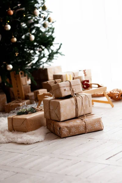 Az ember kézzel készített ajándékot csomagol egy kraft papírba a karácsonyfa alatt. Ajándékok a családnak. Első látásra. Lapos fektetés. — Stock Fotó