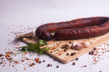 salami sausages from boiled meat on a dark board with pepper, cucumber, tomato, onion and spices. View from above