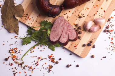 salami sausages from boiled meat on a dark board with pepper, cucumber, tomato, onion and spices. View from above