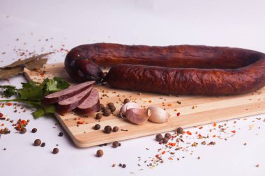 salami sausages from boiled meat on a dark board with pepper, cucumber, tomato, onion and spices. View from above