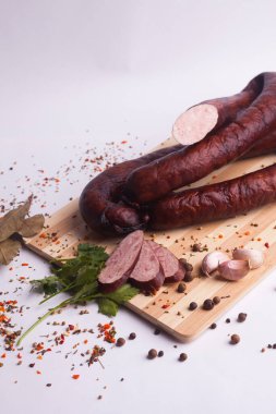 salami sausages from boiled meat on a dark board with pepper, cucumber, tomato, onion and spices. View from above