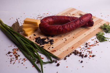salami sausages from boiled meat on a dark board with pepper, cucumber, tomato, onion and spices. View from above