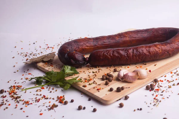 salami sausages from boiled meat on a dark board with pepper, cucumber, tomato, onion and spices. View from above