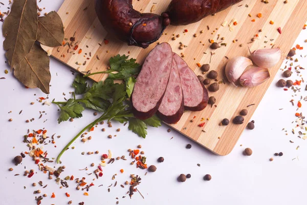 salami sausages from boiled meat on a dark board with pepper, cucumber, tomato, onion and spices. View from above