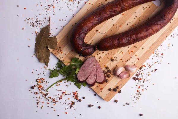 salami sausages from boiled meat on a dark board with pepper, cucumber, tomato, onion and spices. View from above