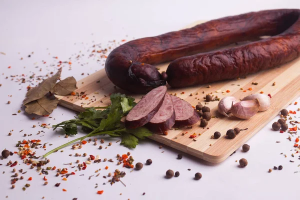 salami sausages from boiled meat on a dark board with pepper, cucumber, tomato, onion and spices. View from above