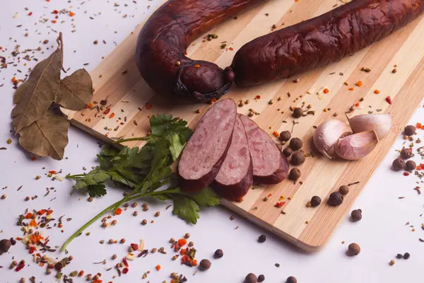 salami sausages from boiled meat on a dark board with pepper, cucumber, tomato, onion and spices. View from above