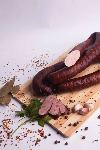 salami sausages from boiled meat on a dark board with pepper, cucumber, tomato, onion and spices. View from above