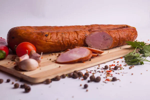 salami sausages from boiled meat on a dark board with pepper, cucumber, tomato, onion and spices. View from above