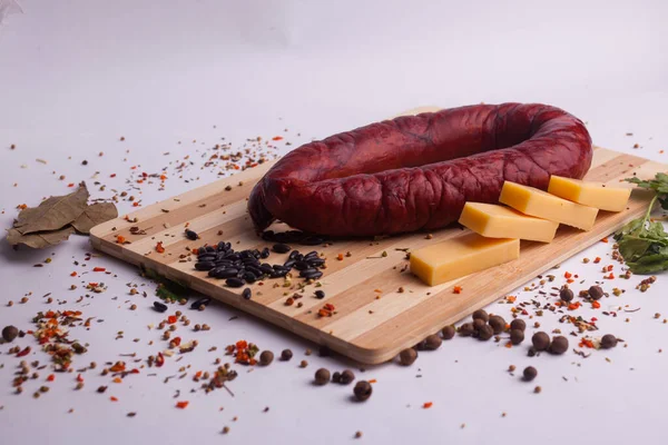 salami sausages from boiled meat on a dark board with pepper, cucumber, tomato, onion and spices. View from above