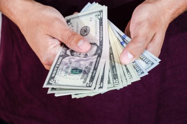 Bir adam bir tomar doları elinde tutuyor. Amerikan Doları