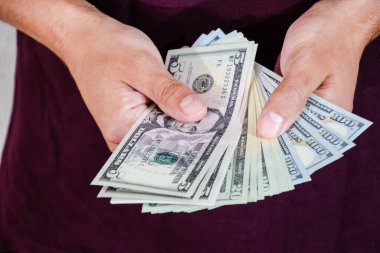 Bir adam bir tomar doları elinde tutuyor. Amerikan Doları