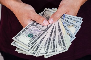 Bir adam bir tomar doları elinde tutuyor. Amerikan Doları