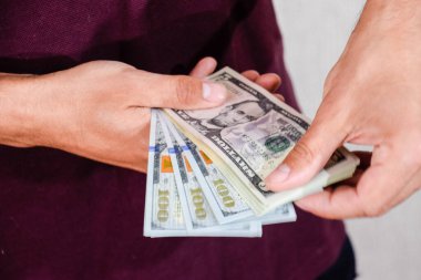 Bir adam bir tomar doları elinde tutuyor. Amerikan Doları